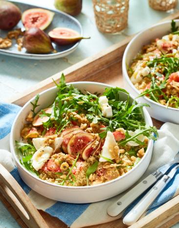 Couscoussalat mit Rucola und Ziegenkäse in zwei Schüsseln.