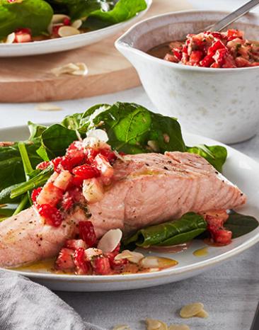 Lachs mit Spinat und Erdbeeren auf zwei Tellern angerichtet.
