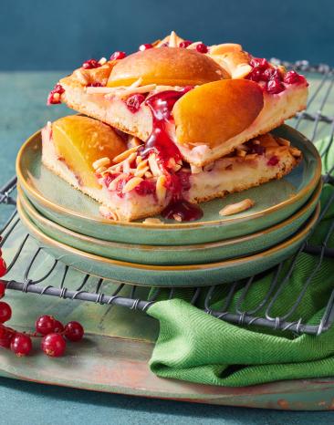 Blechkuchen mit Johannisbeeren und Nektarinen in Stücke geschnitten auf Tellern.