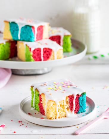Bunter Papageienkuchen mit Zuckerguss in Stücke geschnitten.
