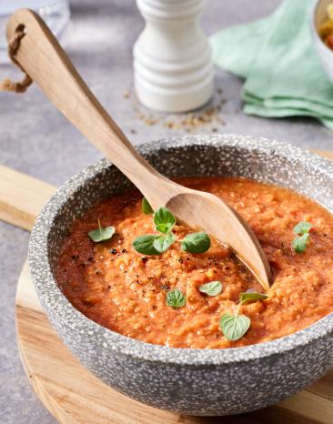 Tomatensauce mit Basilikumblättern und einem Holzlöffel.