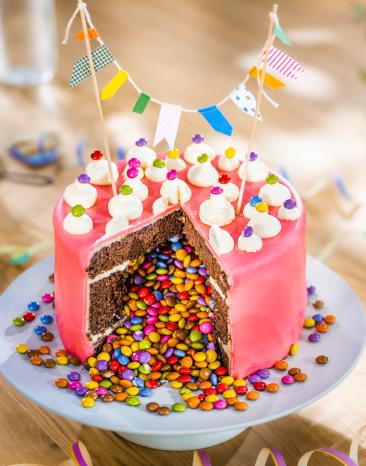 Piñata-Torte angeschnitten mit bunten Schokolinsen in der Mitte.