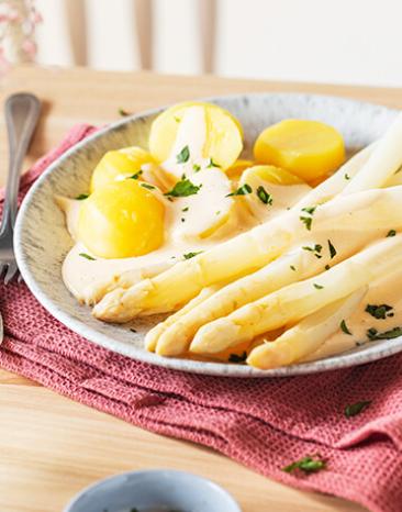 Spargel mit Kartoffeln und Sauce Hollandaise auf einem Teller.