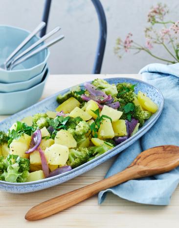 Kartoffelsalat mit Gemüse auf einem Servierteller.