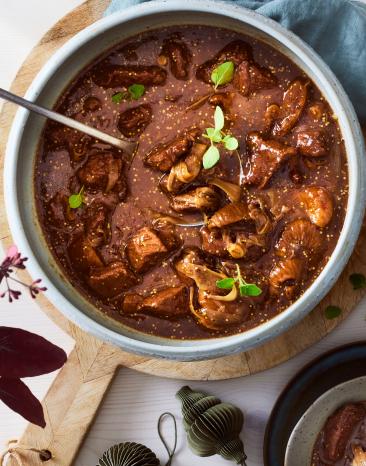 Wildgulasch in einer Schüssel mit frischen Kräutern.