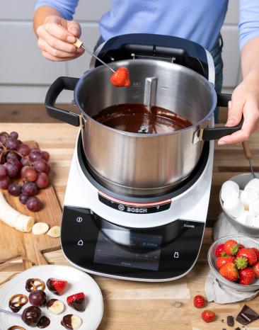In das Schokofondue im Cookit wird eine Erdbeere eingetaucht. In das Schokofondue im Cookit wird eine Erdbeere eingetaucht.