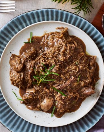Gänsekeule gezupt mit dunkler Sauce auf einem Teller.