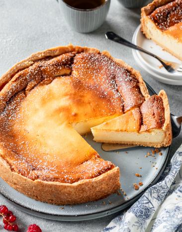 Klassischer Käsekuchen angeschnitten auf Tortenplatte