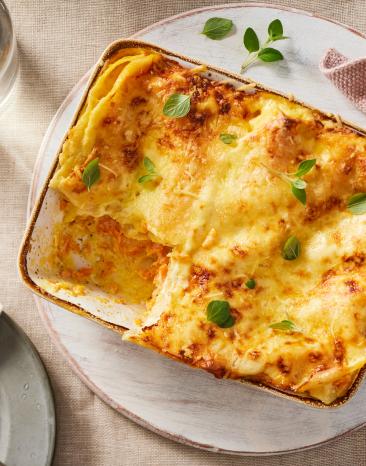 Karotten Lasagne mit Süßkartoffel in einer Auflaufform mit frischen Kräutern.