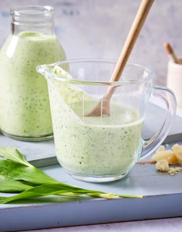 Bärlauchdressing in einem Glasgefäß mit Holzlöffel.