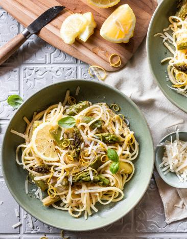 Spaghetti mit Zitronen und grünem Spargel in zwei tiefen Tellern.