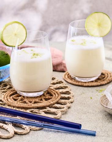 Brazilian Lemonade in cremeweiß in zwei Gläsern mit Limettenscheiben.