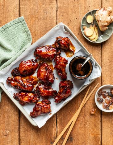 Chicken Wings süß-sauer auf einem Tablett mit Sauce.