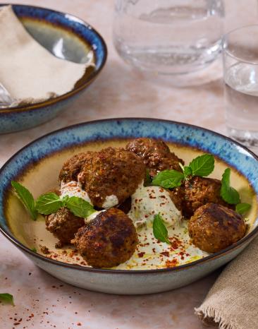 Lamm Frikadellen auf Minzjoghurt in einer bunten Schüssel.