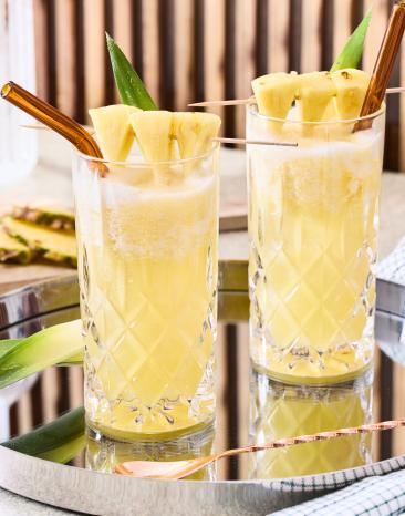 Vigin Pinacolada mit frischer Ananas als Deko in zwei Gläsern mit Stohhalmen.