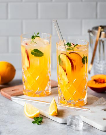 Pfirsich Limonade mit frischen Pfirsichen und Minze in Gläsern.