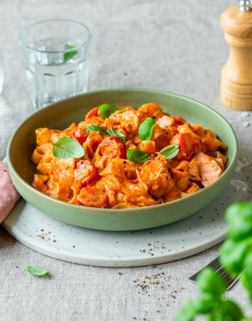Tiefer Teller mit Pasta, Lachs und Tomaten.