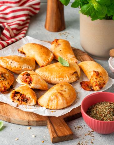 Mini-Calzone mit Schinken und Champignons auf einem gedeckten Tisch.