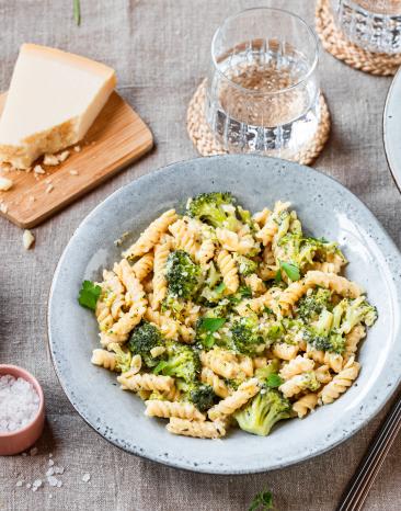 One-Pot-Pasta mit Brokkoli in hellen Schüsseln auf einem gedeckten Tisch.