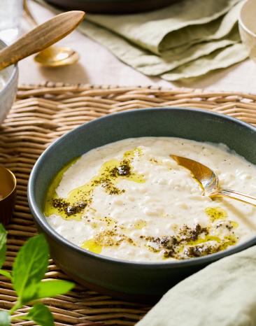 Türkische Joghurtsuppe (Yayla çorbası) in einem tiefen Teller auf einem gedeckten Tisch.
