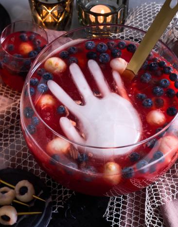 Halloween-Bowle mit Hand in roter Flüssigkeit.