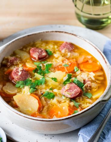 Spitzkohleintopf mit Wurst in einem tiefen Teller.