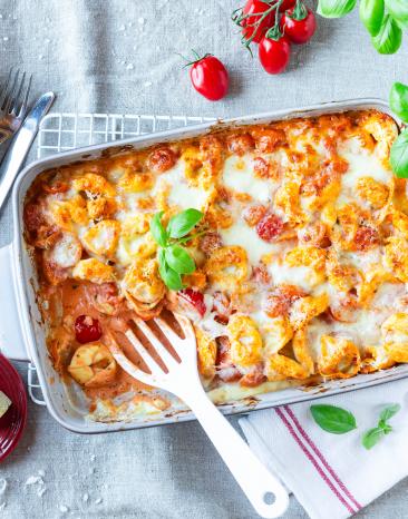 Tortelliniauflauf Tomate-Mozzarella in einer Auflaufform mit frischem Basilikum getoppt. Tortelliniauflauf Tomate-Mozzarella in einer Auflaufform mit frischem Basilikum getoppt.