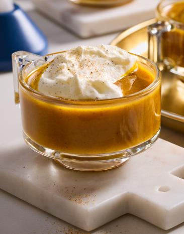 Heißer Butter-Rum mit Kürbis mit Haube in Glastassen.