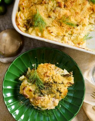 Schwedischer Kartoffelauflauf (Janssons Frestelse) in einer Auflaufform und auf einem grünen Teller.