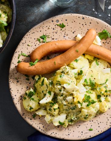 Würstchen mit Kartoffelsalat auf einem Teller.