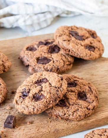 Vegane Chocolate Chip Cookies auf einem Holzbrett.