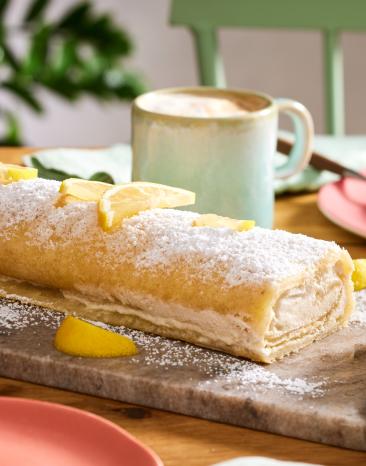 Vegane Zitronenrolle auf einer Kaffeetafel, abgeschnitten.