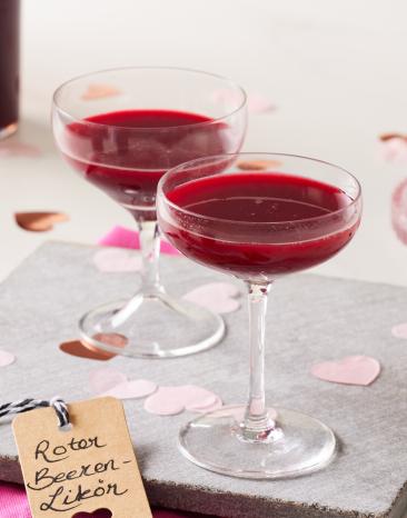 Roter Beerenlikör in Flaschen und eingeschänkt in Likörgläsern.