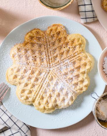 Vegane Herzwaffel mit Puderzucker auf einem Teller.