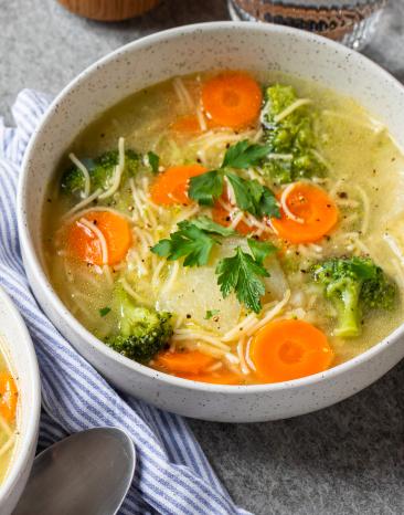 Frühlingssuppe mit buntem Gemüse in Schüsseln.
