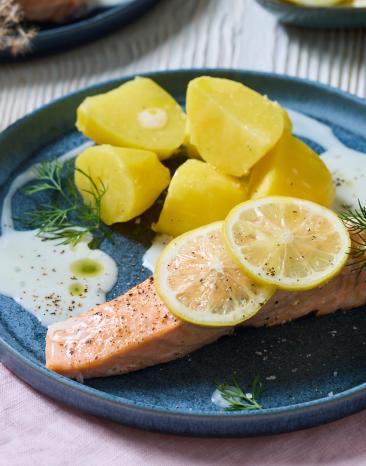 Gedämpfter Lachs mit Zitronensauce auf Tellern.