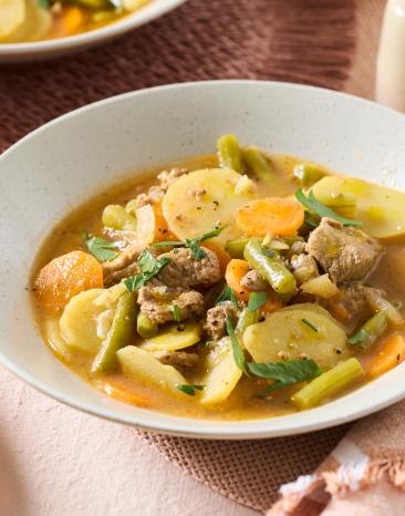 Lammeintopf mit Gemüse und Sud in tiefen Tellern.