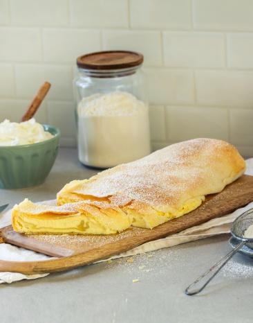 Quarkstrudel auf einem Holzbrett mit Puderzucker.