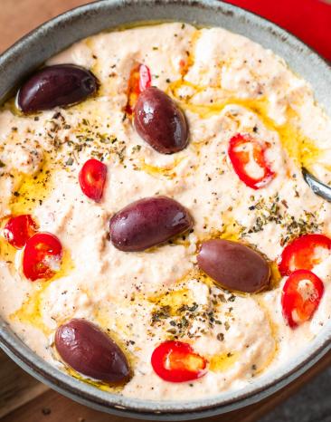 Chtipiti (Griechische Schafskäsecreme) mit Oliven in einer Schale.