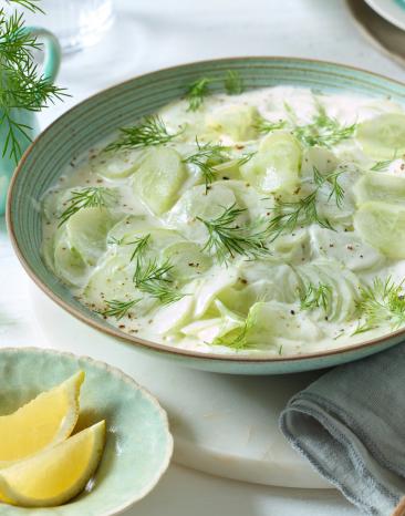 Gurkensalat mit saurer Sahne mit Dill serviert.