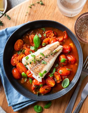 Kabeljau Filet auf Tomaten Sauce auf einem Teller.
