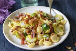 Nudeln mit Rosenkohl und Speck auf einem Teller.