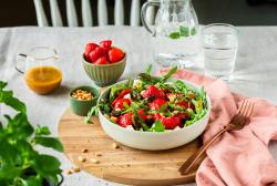 Spargelsalat mit Erdbeeren in einer Schüssel auf einem gedeckten Tisch.