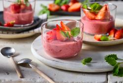 Erdbeerpudding mit frischen Erdbeeren und Minze garniert in Glasschälchen angerichtet.
